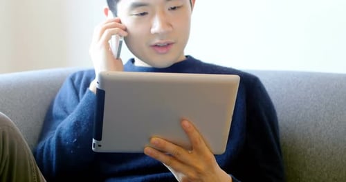 Young Adult Using Tablet While Talking on Phone