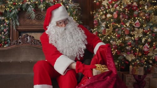 Santa Claus Putting Gift into Sack on Couch