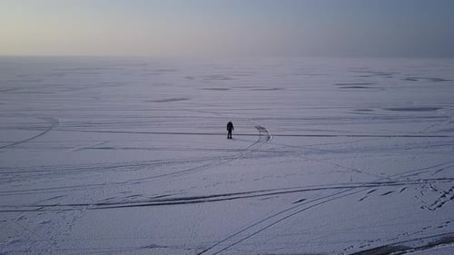 Woman Walking Over Wide Icy Arctic Lake