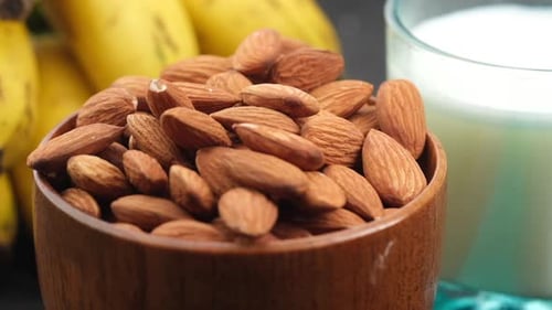 Close Up of Almond Nuts in a Bowl Banana and Milk on Table