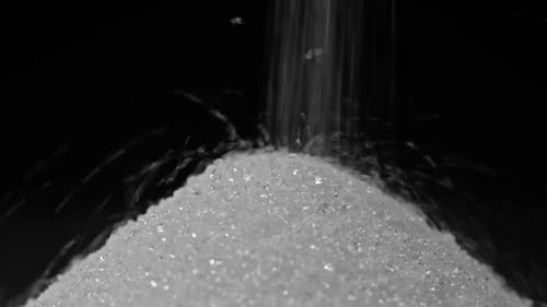 White Sugar Pile Filling Up On Black Background