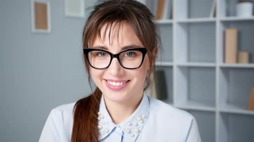 Smiling Young Woman in Glasses Poses in Office