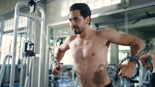 4K Caucasian man bodybuilder pulling weight lifting machine at gym.
