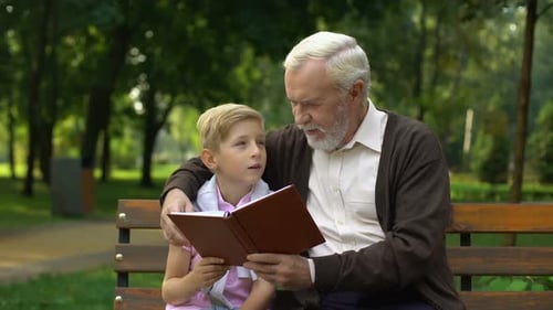 Senior Man and Child Reading Together in Park