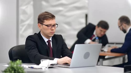 Confident Male Office Worker in Suit Working on Laptop at Modern Interior