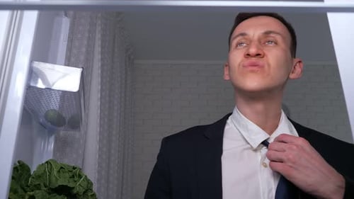 Man in Suit Eats Midnight Snack from Fridge