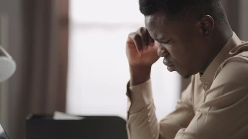 Tired Male Black Student or Pupil is Viewing on Screen of Laptop in Room Thinking and Suffering