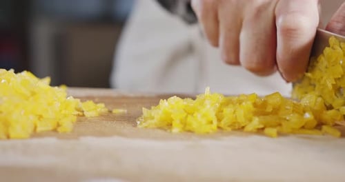 Slow motion close up of a chef knife slicing a yellow bell pepper