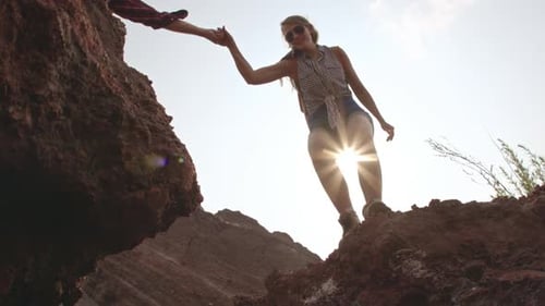 Woman Reaching Down from Clay Mountain for Assistance