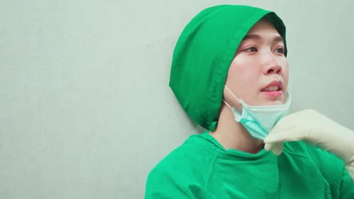 Medical Professional in Scrubs Wipes Sweat from Brow