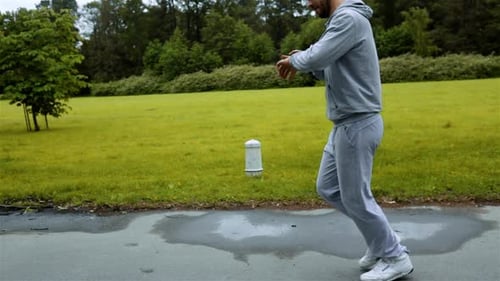 Man Running in Forest Woods Training and Look at Computer Clock on His Arm
