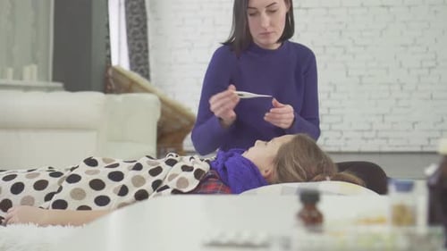 Woman Checks Sick Girl's Temperature at Home