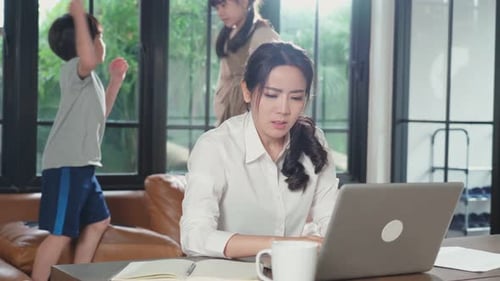 La madre pierde la concentración en el trabajo en la computadora y se siente frustrada porque los niños hacen ruido.