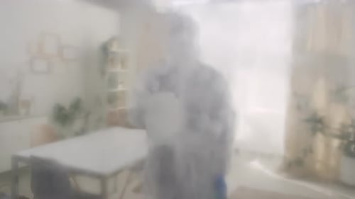 Femme en équipement de protection pulvérisant un désinfectant sur une caméra