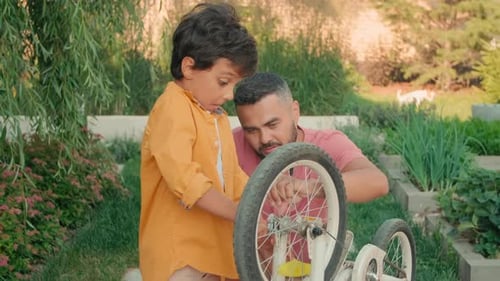 Man and Child Repairing Bicycle Outdoors