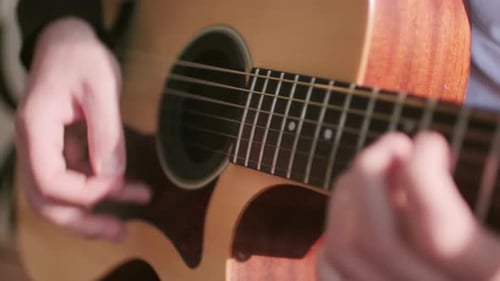 Person Playing Acoustic Guitar in Close Up