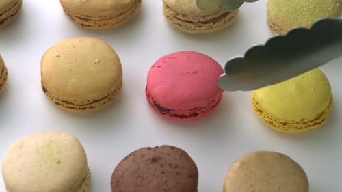 Colorful Macarons being Picked Up by Tongs