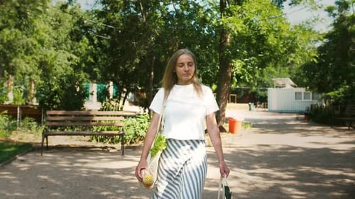 Mujer joven llevando verduras y frutas en bolsas de compras orgánicas de malla reutilizables caminando