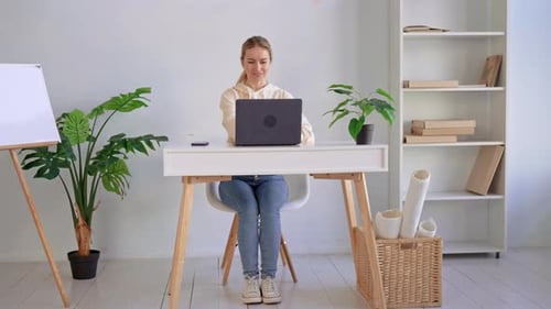 Woman closes laptop and relaxes in home office