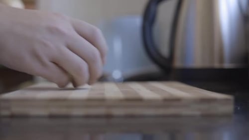 Static shot of a man placing onions ona wooden chopping board
