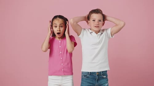 Studioporträt eines emotionalen kleinen Jungen und Mädchens, die sich aufgeregt und schockiert fühlen