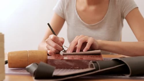 Young Adult Crafting Leather Goods at Indoor Table