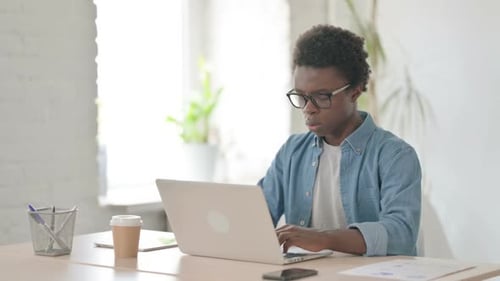 Young African Man Having Neck Pain While Using Laptop in Office