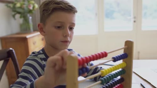 Niño aprendiendo matemáticas en un ábaco sentado a la mesa en un hogar cómodo 4k