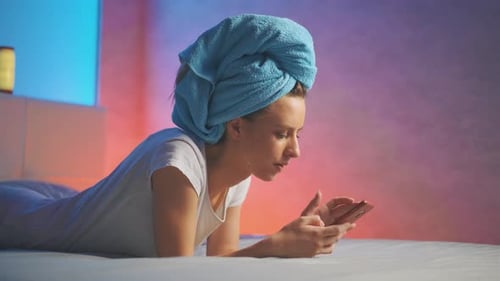 Woman in Towel Using Smartphone in Bedroom