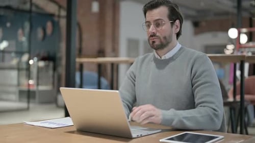Young Man Having Back Pain While Using Laptop in Office