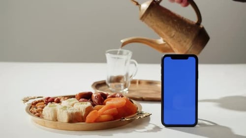 Smartphone de chá e doces turcos com tela azul Chroma Key Bebida quente em copo Armudu tradicional