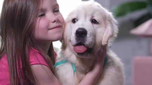 Little Girl Cuddling Adorable Golden Retriever Puppy