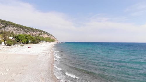 Aerial View of the Mountain Coast with Buildings Among the Trees and the Bright Blue Sea with