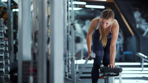 Athletic Woman Working Out with Dumbbells in Gym