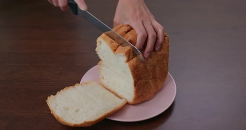 Crusty White Bread Being Sliced on Plate