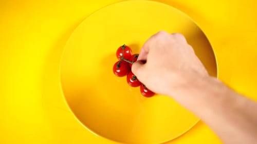 Reife frische saftige Bio-Kirschtomaten auf einem gelben Teller. Rote Kirschtomaten in Gelb strukturiert