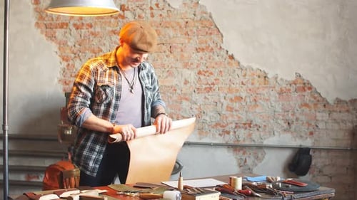 Man Unrolling Leather in Sunny Workshop