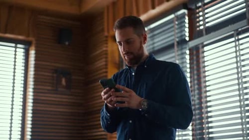 Man Using Smartphone in Wood Paneled Interior