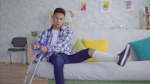 Young Man with Broken Leg Sits on Couch