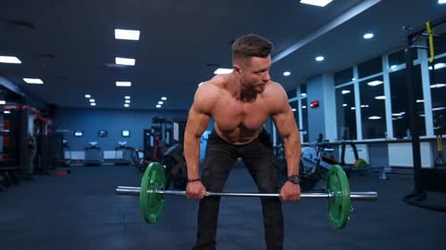 Male athlete trains with barbell in empty gym with modern equipment. Slow motion.
