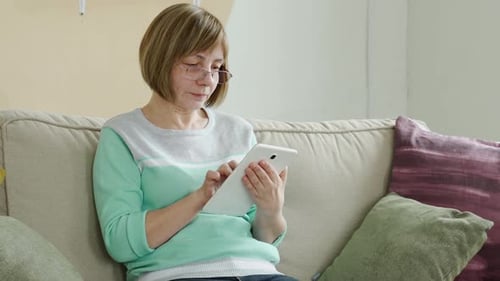 Woman Using Tablet on Couch at Home