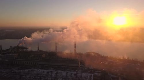 Industriezone mit einem großen rot-weißen Rohr. Dicker weißer Rauch wird aus dem Fabrikrohr eingegossen