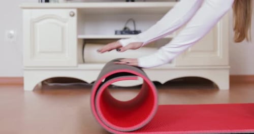 Woman Unrolls Yoga Mat on Wooden Floor
