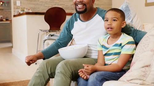 Father and Son Watching TV and Eating Popcorn
