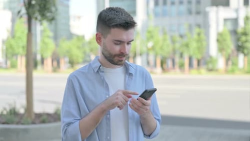 Young Adult Using Mobile Phone on City Street