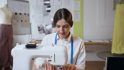 Junge Schneiderin arbeitet im Sew Studio an der Nähmaschine