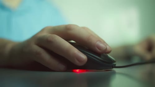 Close up of a man hand works at home in the evening, clicks on the buttons of a computer mouse