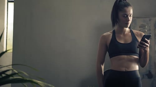 Athletic Woman Using Smartphone in Gym