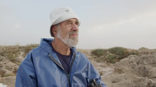 Old fisherman looking into the ocean using his binoculars