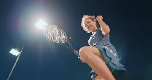 Girl Playing Tennis Under Bright Lights at Night